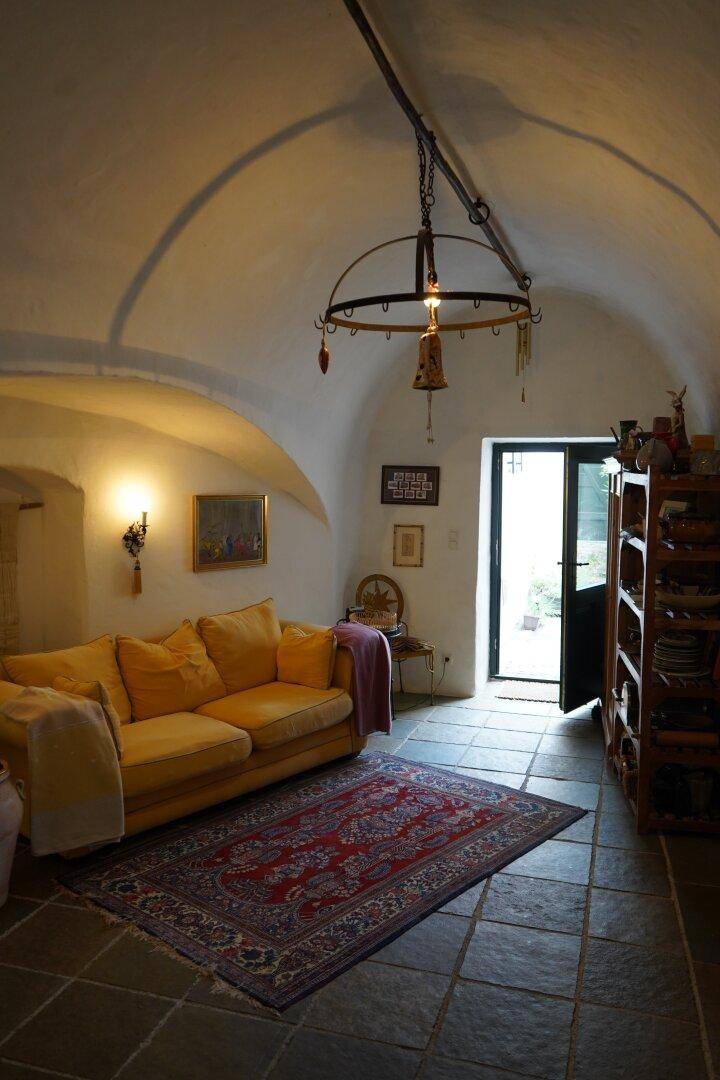 Gemütliches Wohnzimmer mit gelbem Sofa, Gewölbedecke und einem traditionellen Teppich.