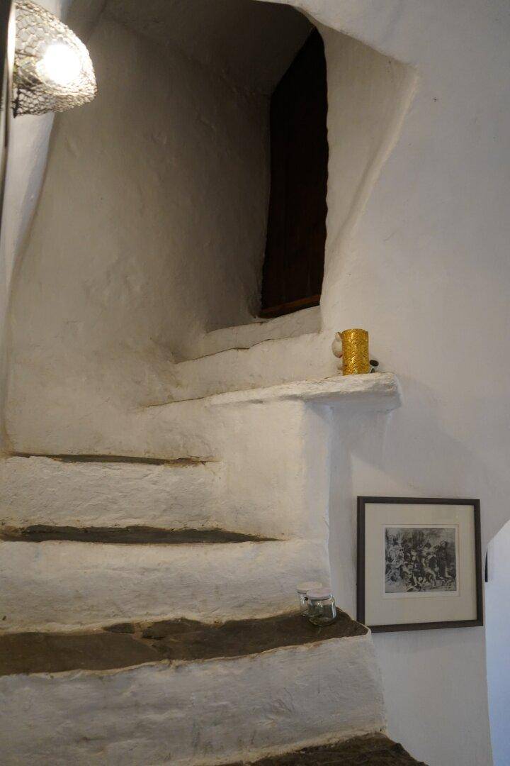 Historische Steintreppe mit weiß getünchten Wänden, die nach oben führt.