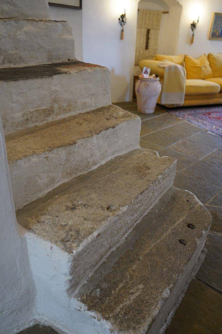 Detailaufnahme einer rustikalen Steintreppe mit Blick auf ein angrenzendes Wohnzimmer.