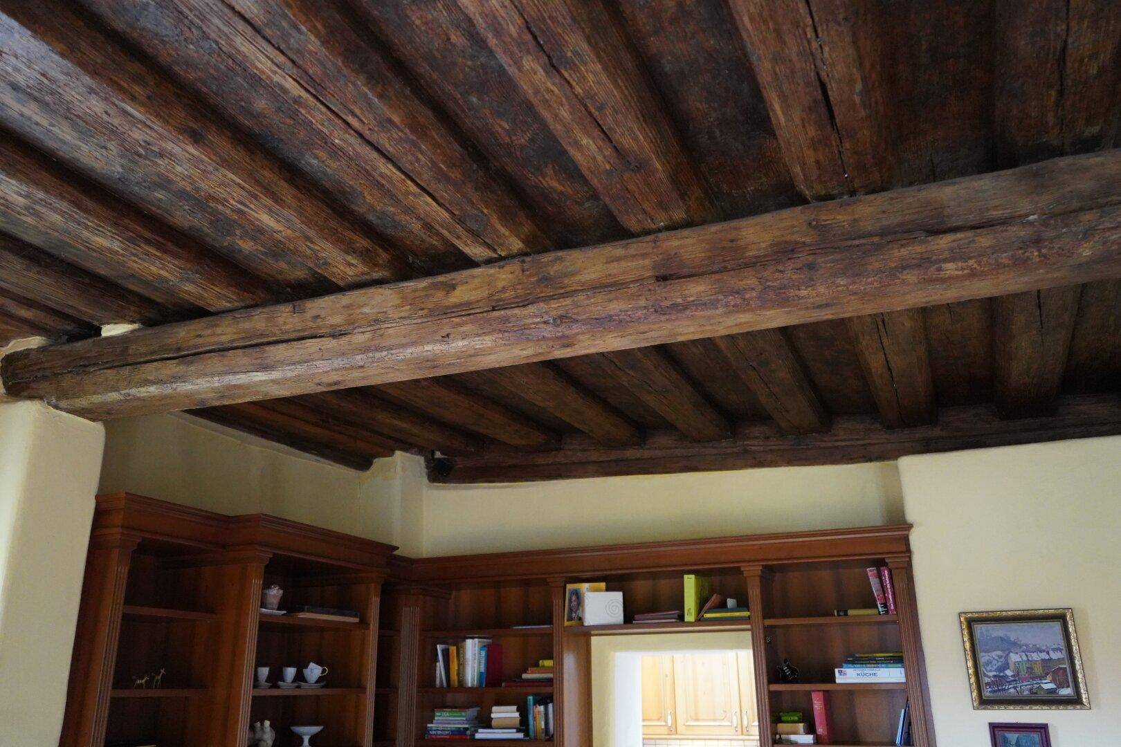 Detailaufnahme einer rustikalen Decke mit alten, dunklen Holzbalken.