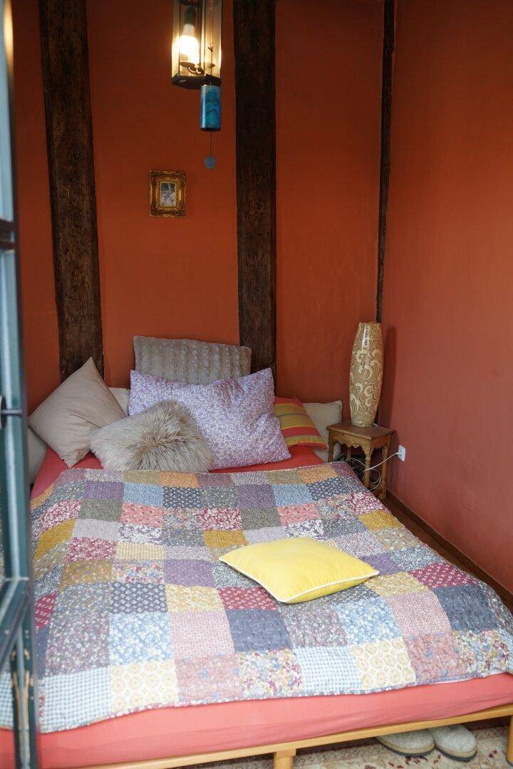 Gemütliches Schlafzimmer mit einem Bett, bunten Patchwork-Decken und freiliegenden Holzbalken.