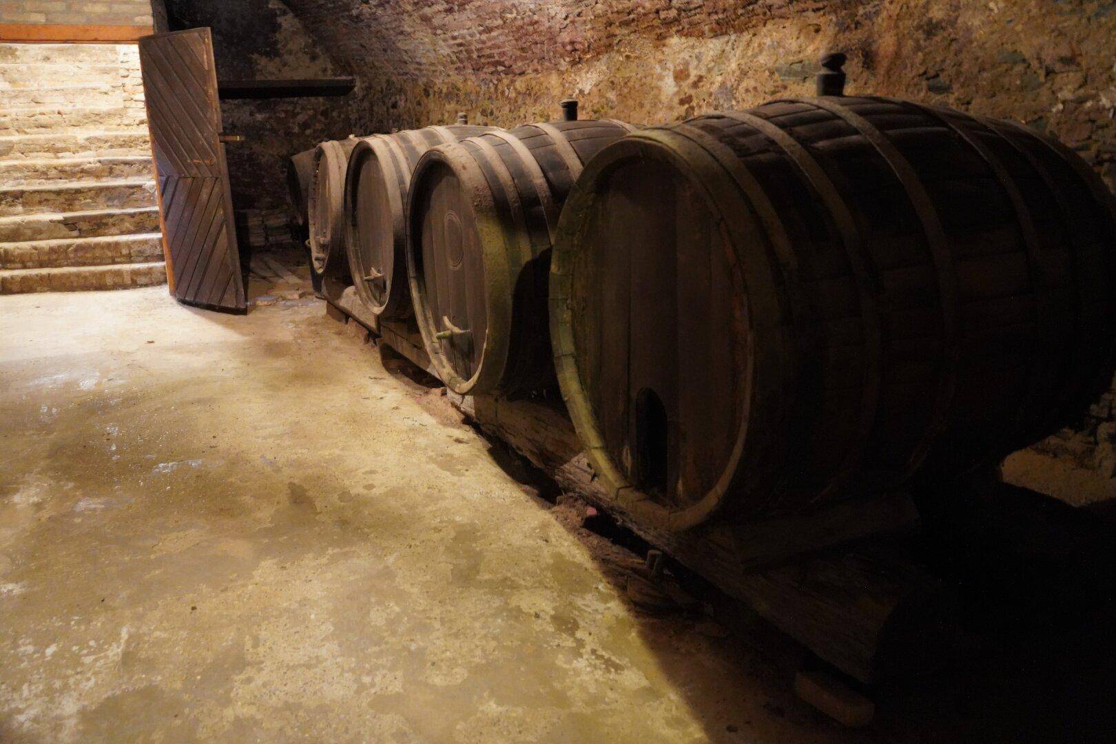 Historischer Weinkeller mit großen Holzfässern und rustikalen Steinmauern, die eine authentische Atmosphäre schaffen.