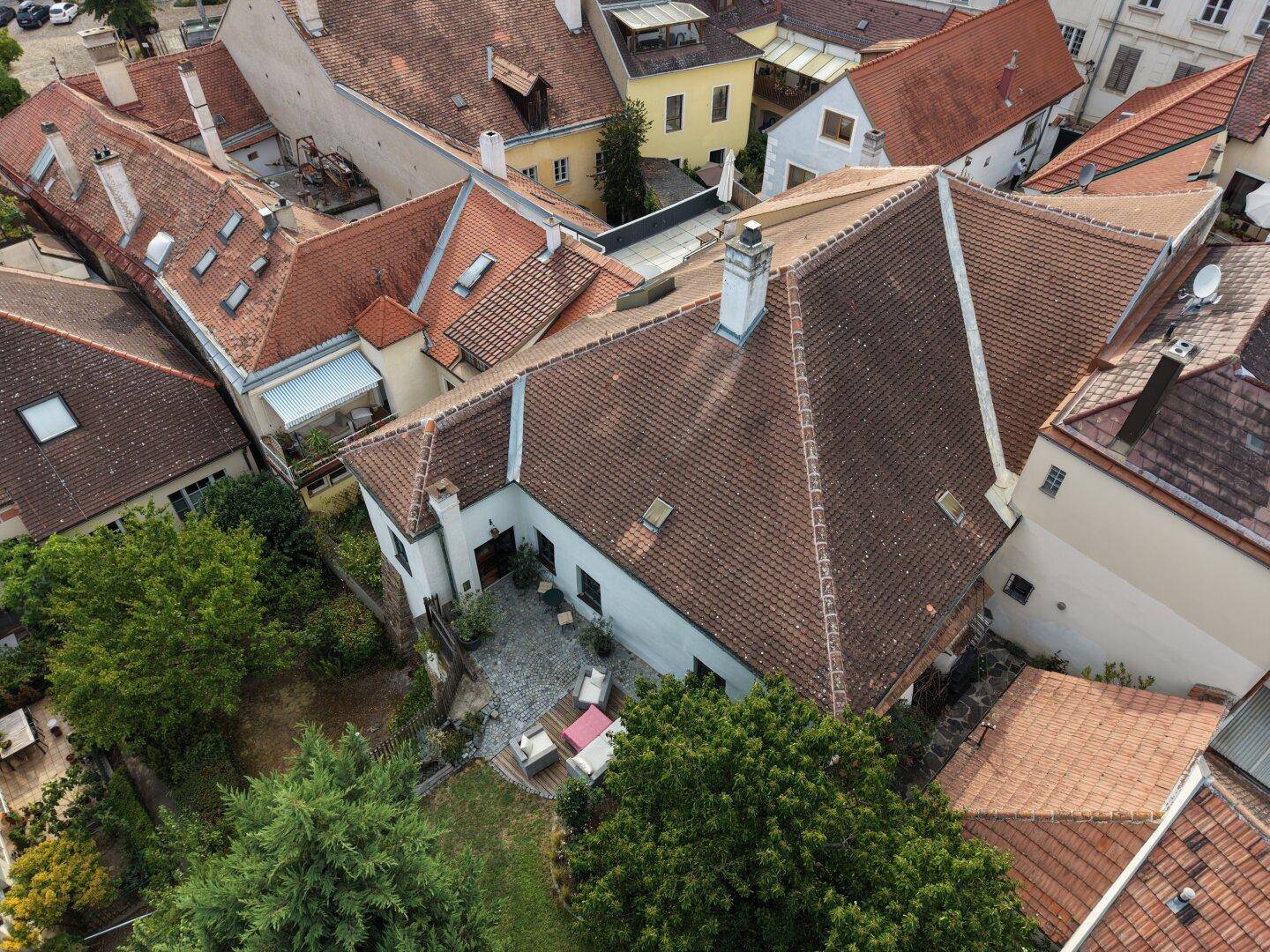 Luftaufnahme des Anwesens mit Innenhof, Garten und umliegenden Dächern in einer historischen Siedlung.