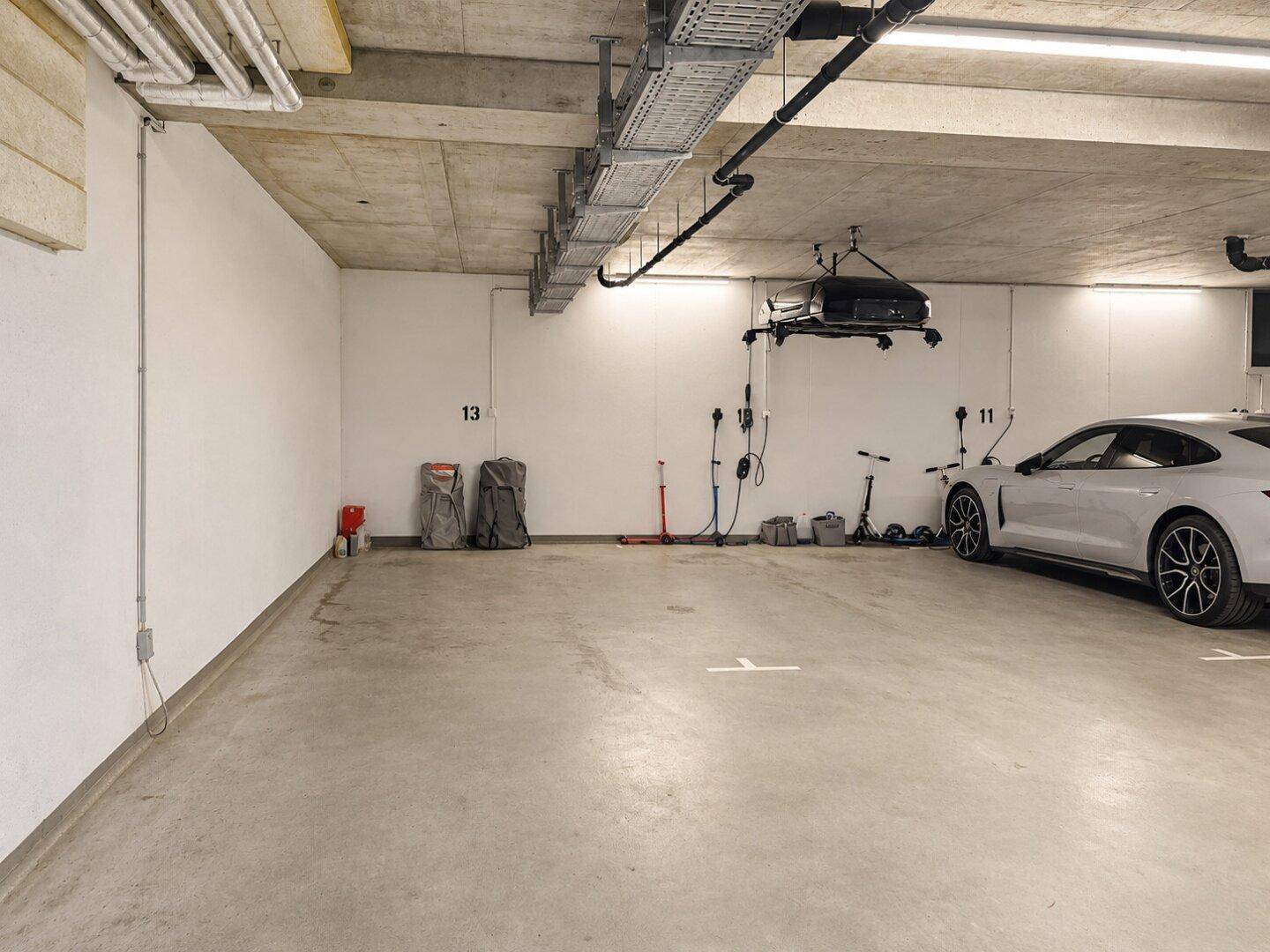 Geräumige Tiefgarage mit Betonboden und Ladestationen für Elektrofahrzeuge.