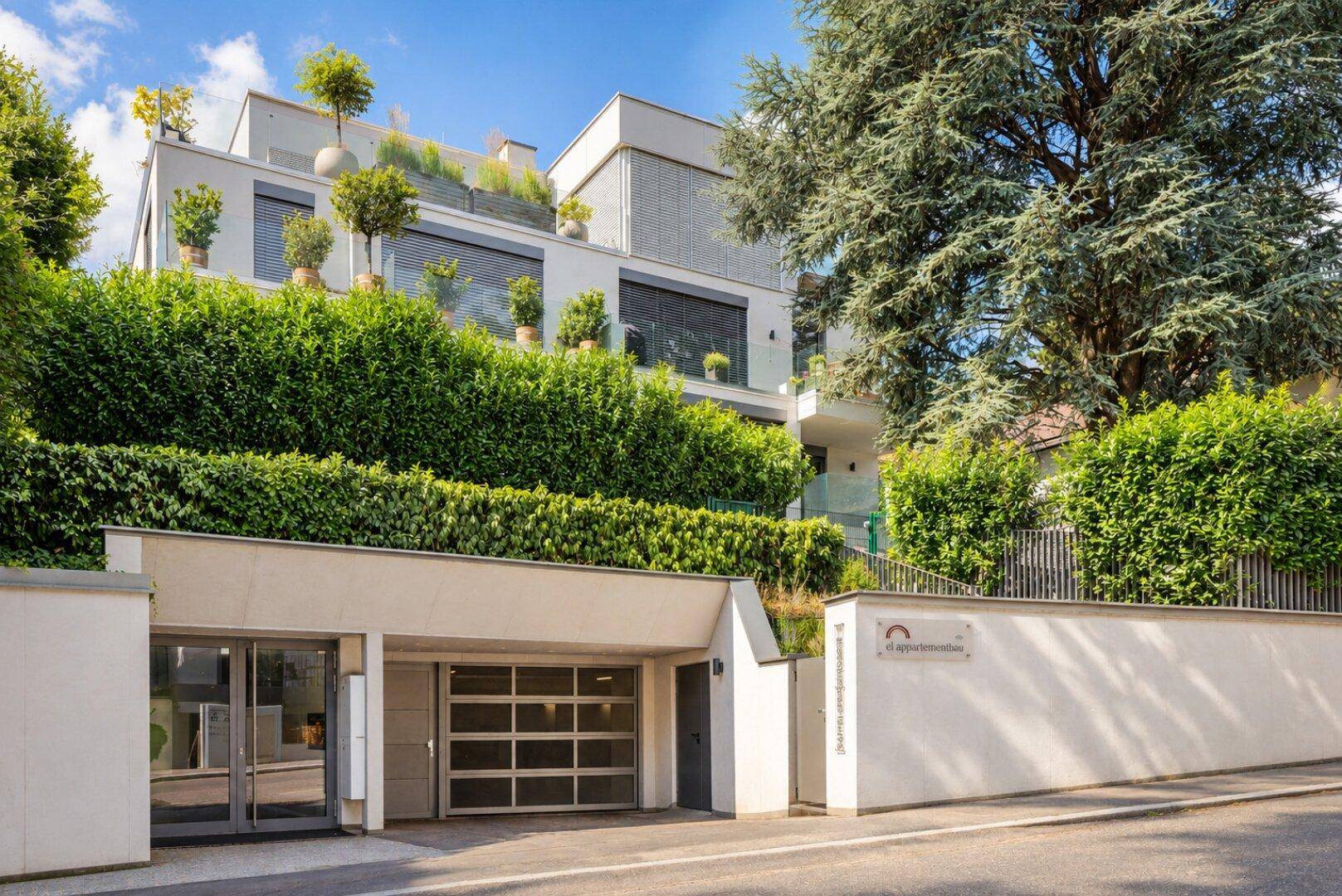 Moderne Wohnanlage mit Tiefgaragenzufahrt und begrünten Terrassen.