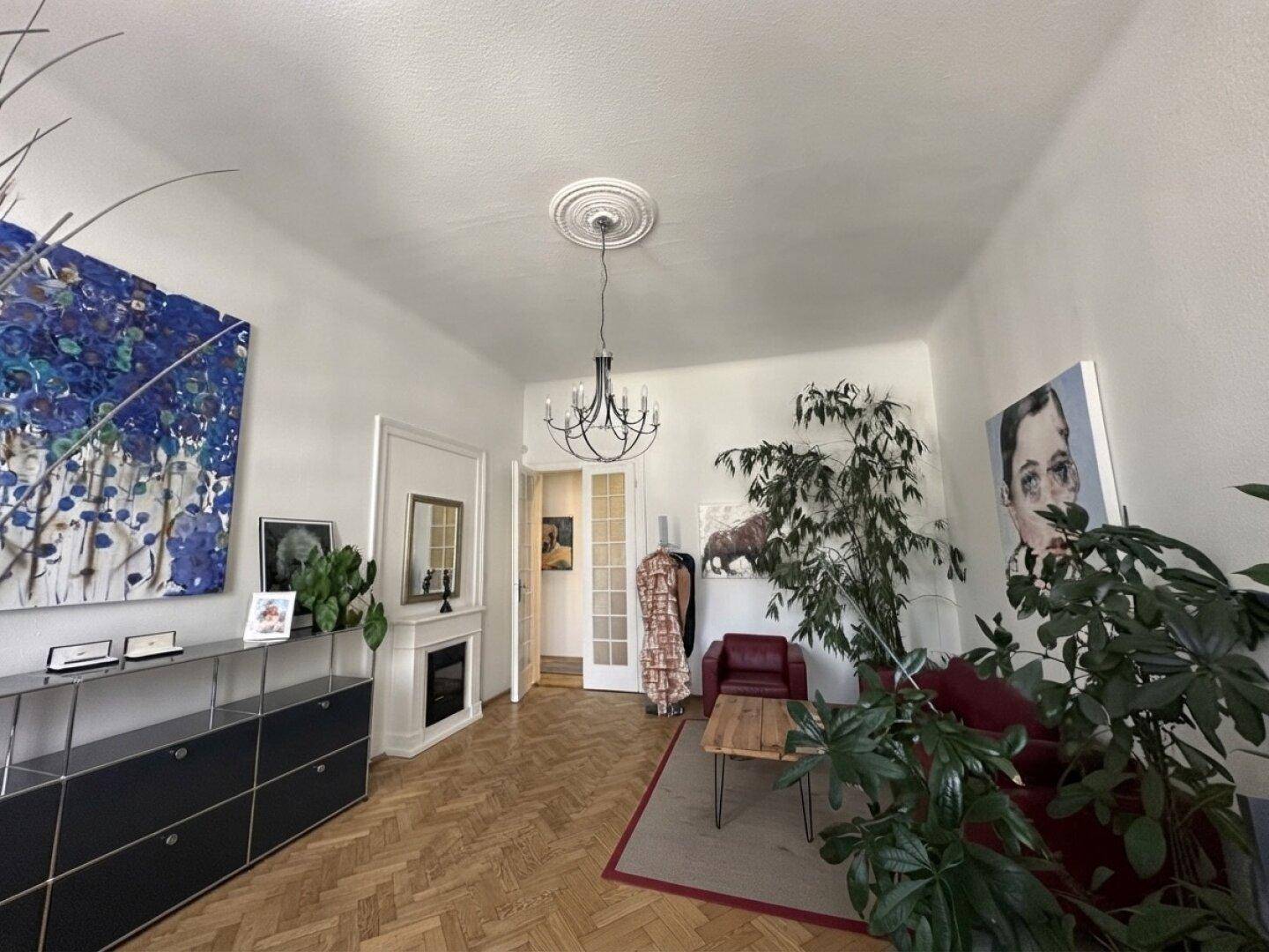 Helles Büro mit Fischgrätparkett, Kamin und großen Pflanzen als Dekoration.