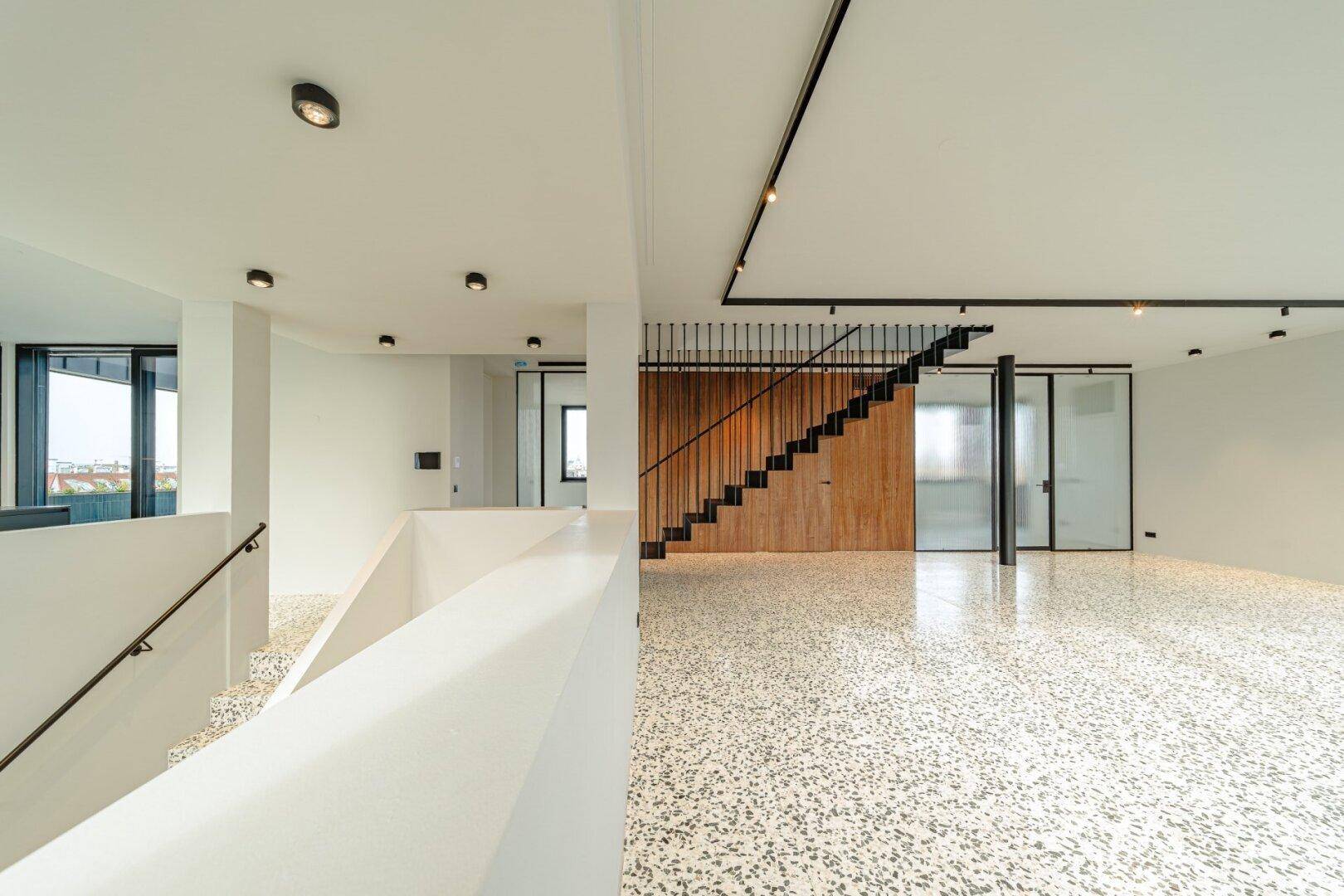 Heller, offener Eingangsbereich mit moderner Treppe und Terrazzoboden.