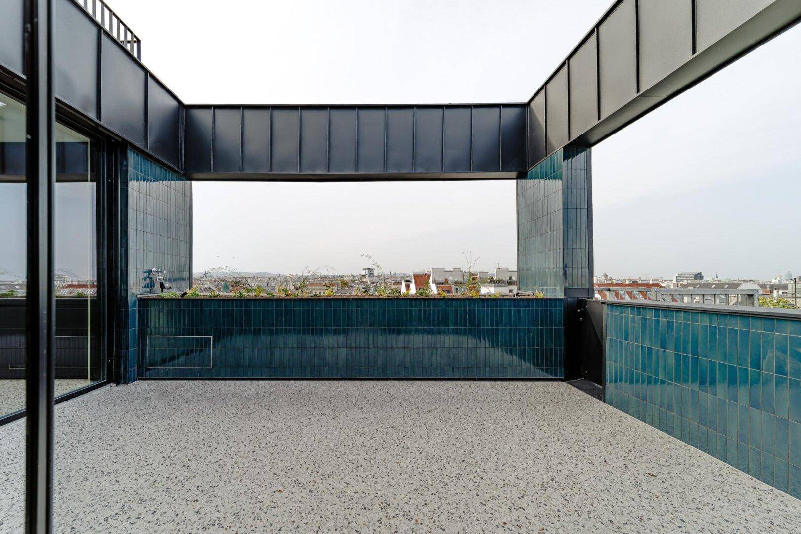 Überdachte Loggia mit blauen Fliesen und Blick auf die Stadt.
