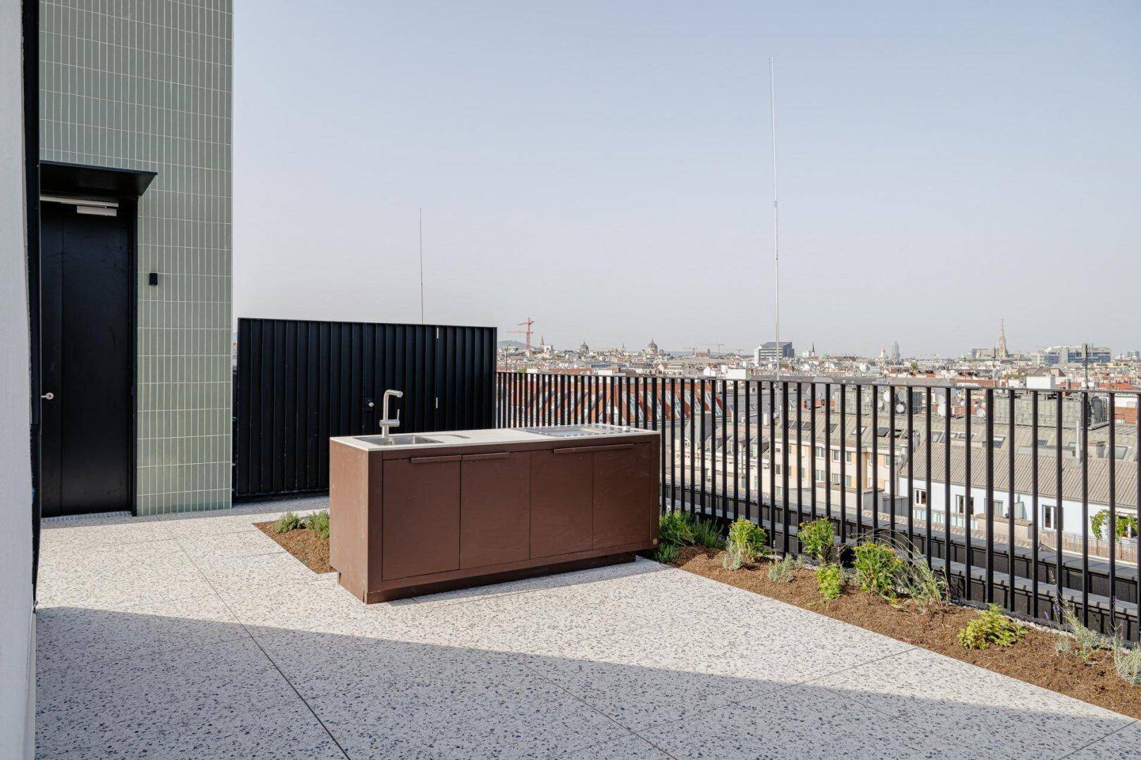 Geräumige Dachterrasse mit Außenküche und weitem Blick über die Stadt.