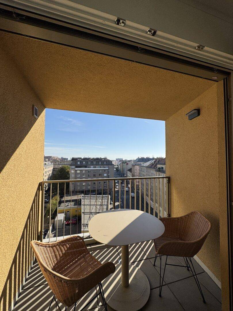 Sonniger Balkon mit Sitzgelegenheiten und einem weiten Blick über die Stadt.