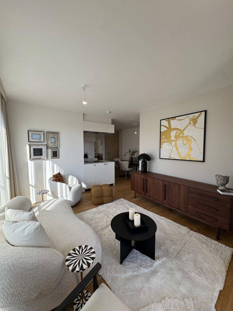 Heller Wohnbereich mit stilvollem Sofa, Sideboard und offenem Übergang zur Küche.