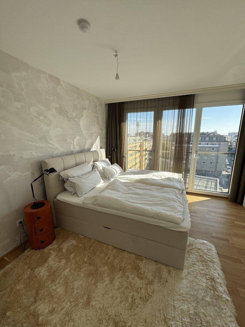 Gemütliches Schlafzimmer mit großem Bett, Holzboden und weitem Blick durch die Fenster.