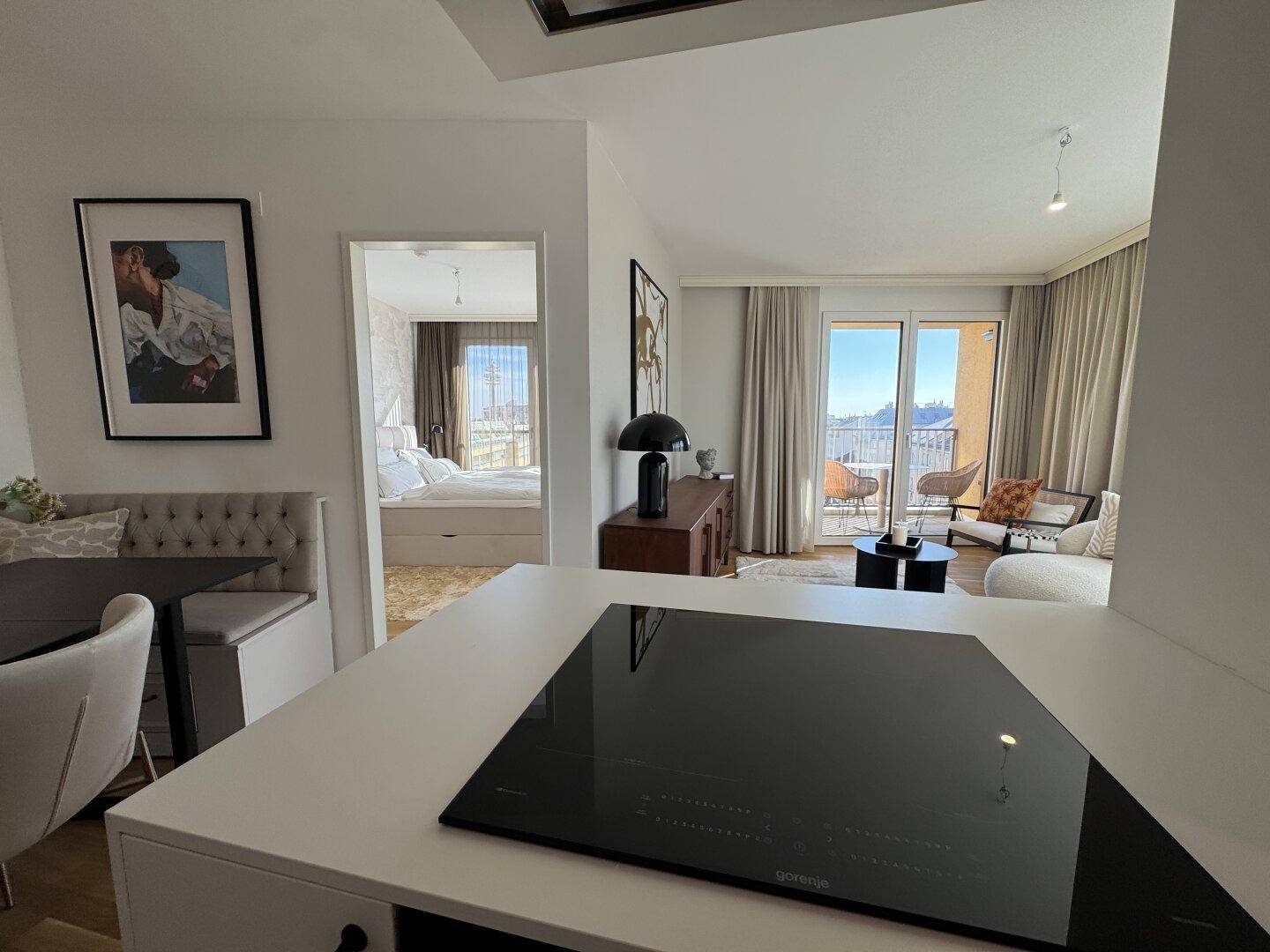 Offener Wohn- und Essbereich mit Blick auf das Schlafzimmer und den sonnigen Balkon.