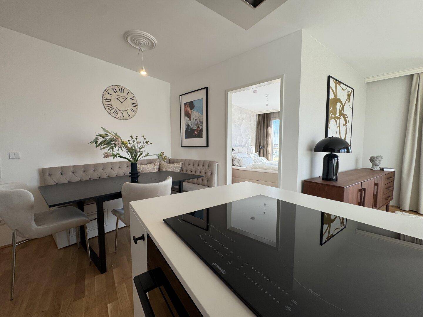 Essbereich mit Sitzbank und Tisch, angrenzend an die moderne Küche und Schlafzimmer.