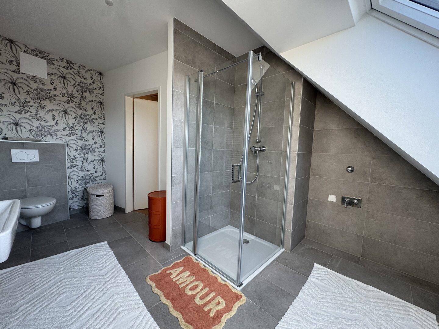 Geräumiges Badezimmer mit Duschkabine, Toilette und modernem Fliesenboden.
