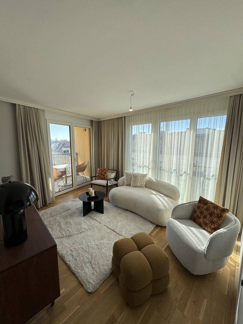 Geräumiges Wohnzimmer mit bequemen Sitzmöbeln, Holzboden und viel Tageslicht.