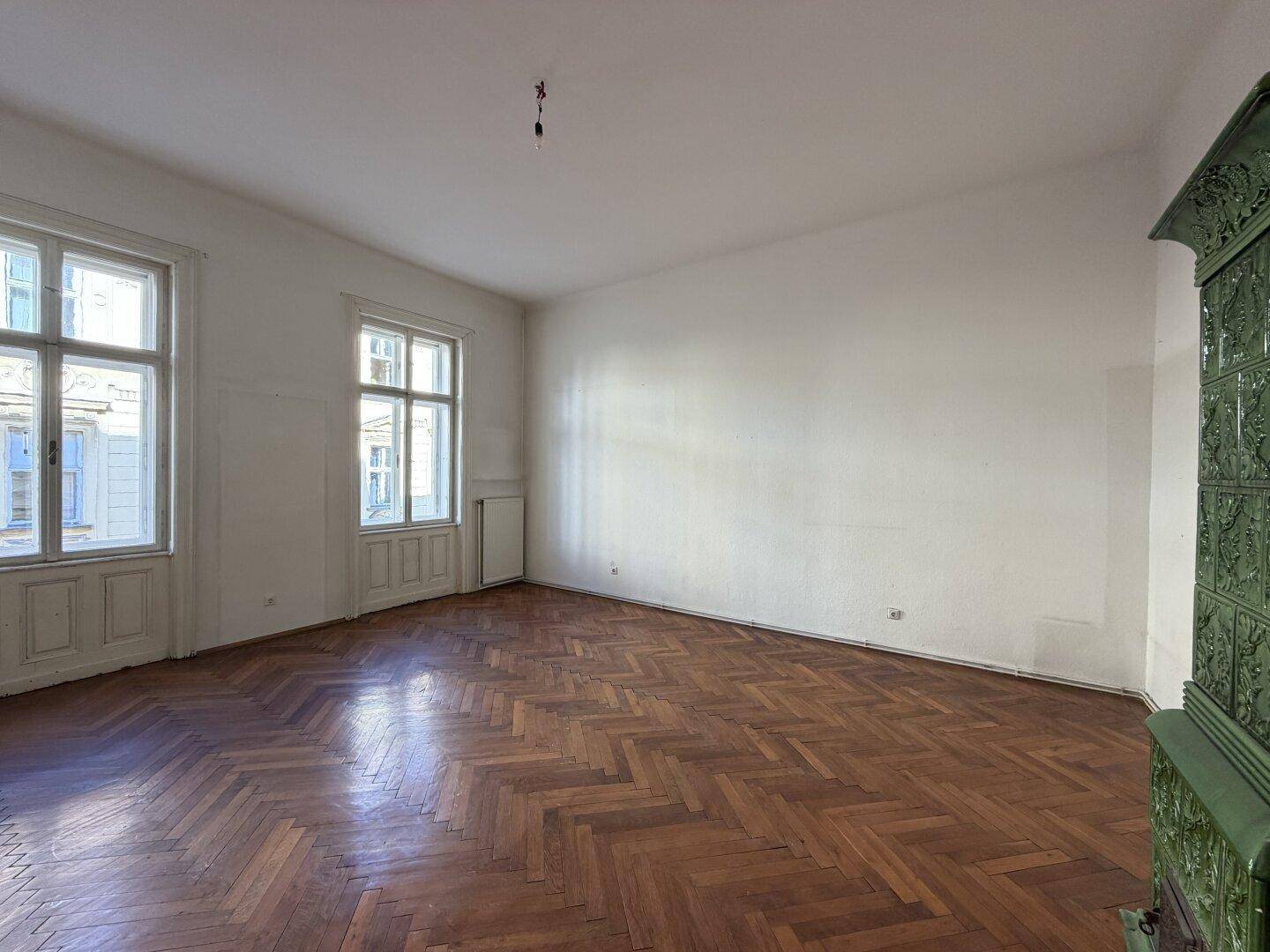 Großes Wohnzimmer mit traditionellem Kachelofen und klassischem Fischgrätparkett.