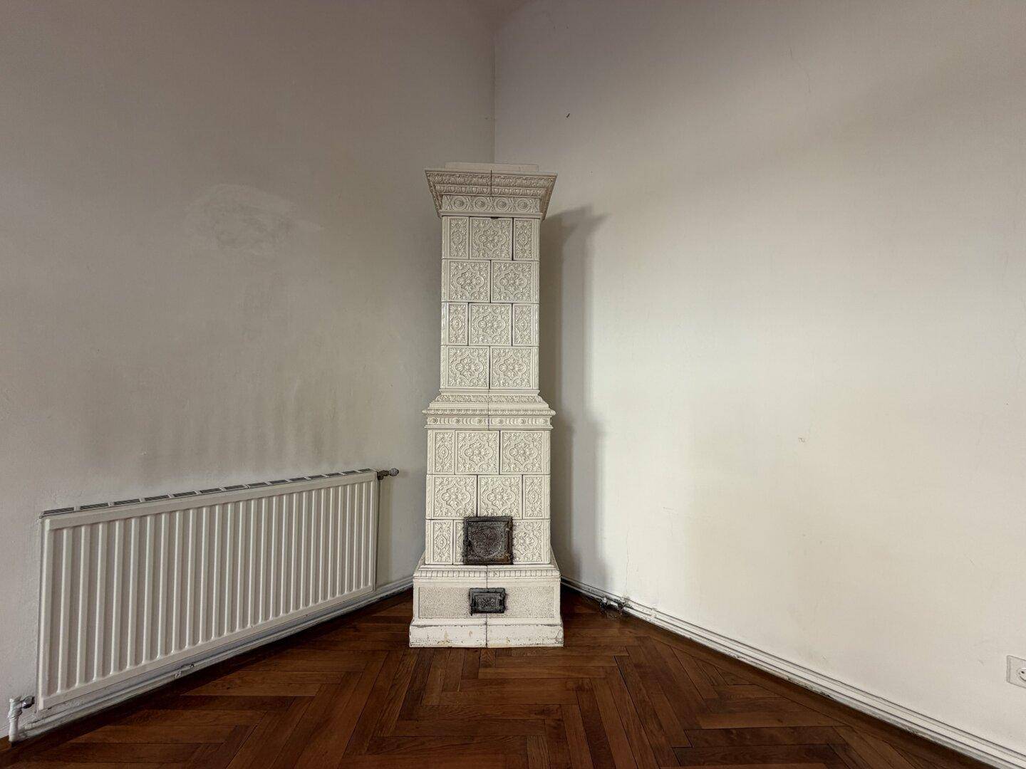 Detailansicht eines traditionellen weißen Kachelofens in einer Ecke des Wohnzimmers.