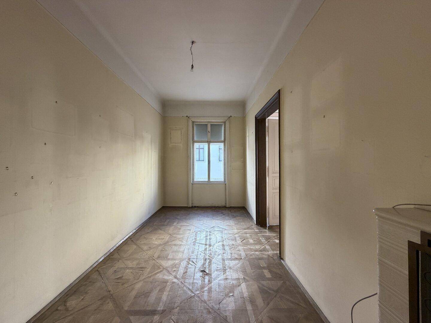 Großer, heller Raum mit Parkettboden und hohen Decken, ideal für Wohn- oder Schlafzimmer.