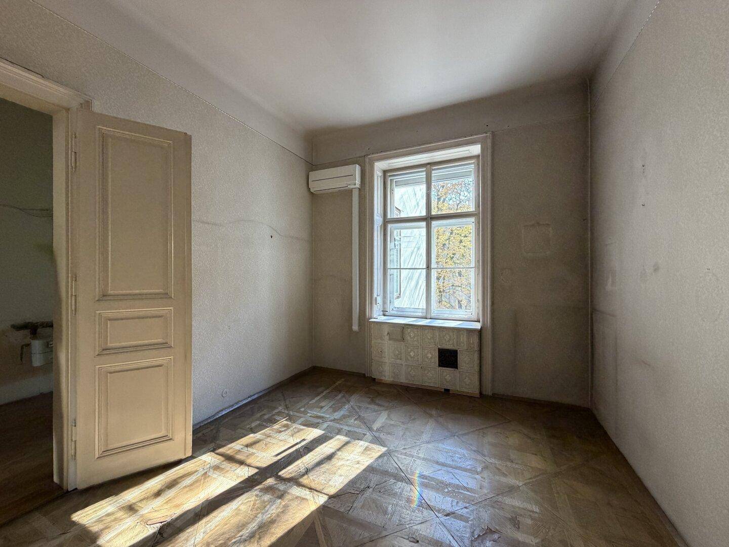Geräumiger Innenraum mit Parkettboden und Fenster, das viel Tageslicht hereinlässt.