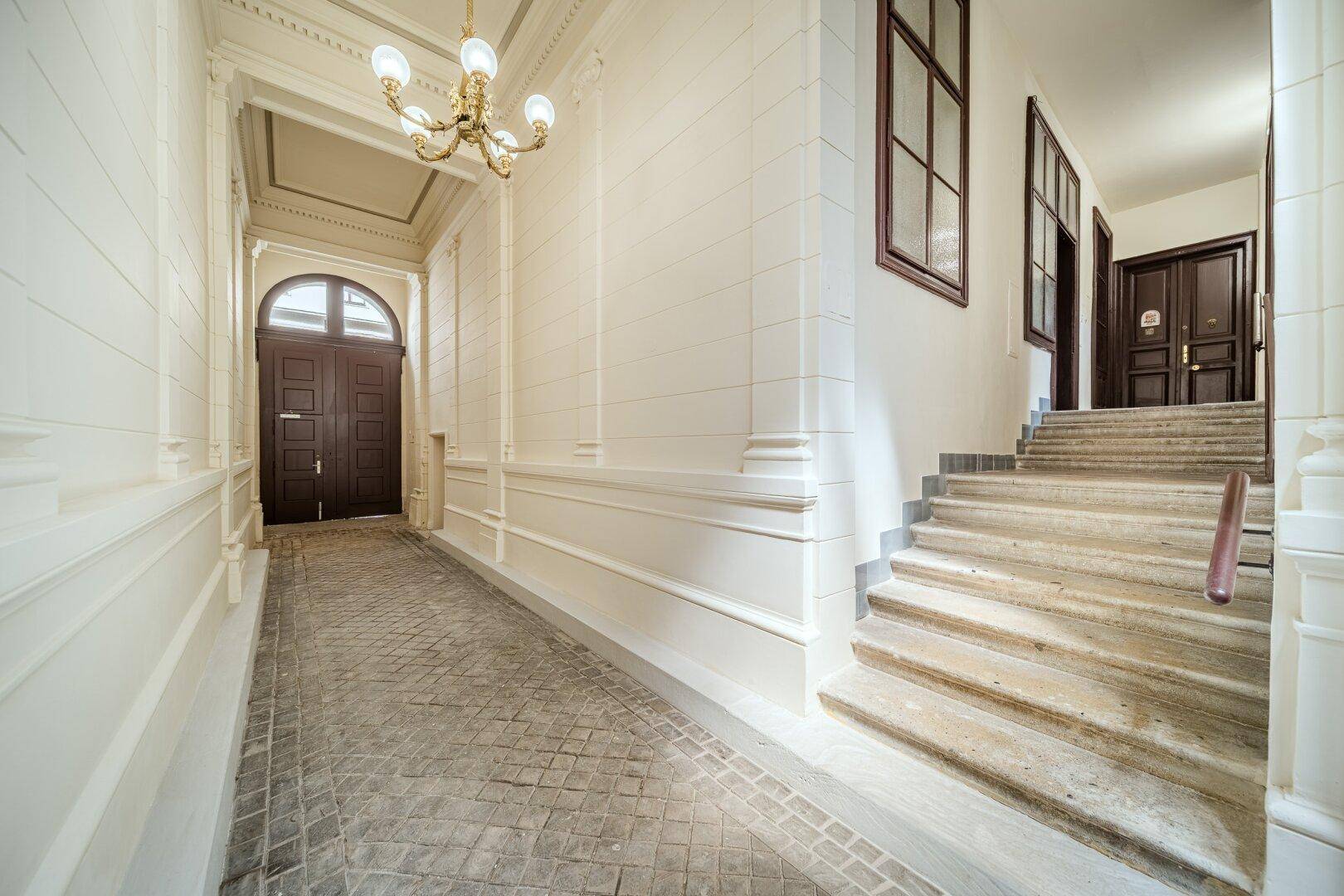 Heller Eingangsbereich mit Steinfliesen und einer Treppe, die zu den oberen Etagen führt.