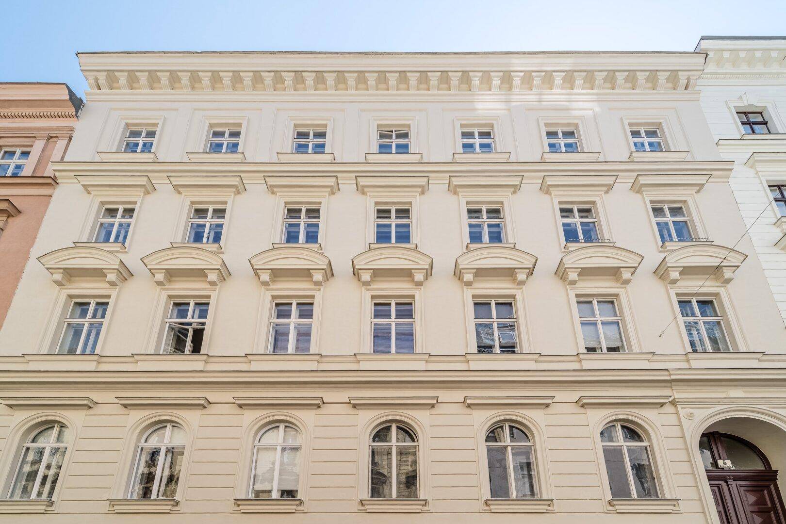 Elegante Altbaufassade mit vielen Fenstern und dekorativen Elementen in der Stadt.