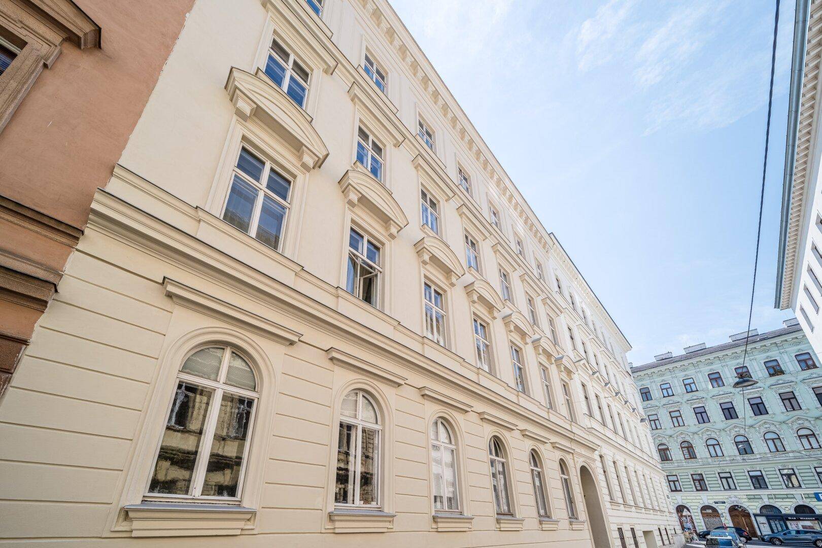 Seitenansicht eines eleganten Altbaus mit vielen Fenstern und Blick auf die Straße.