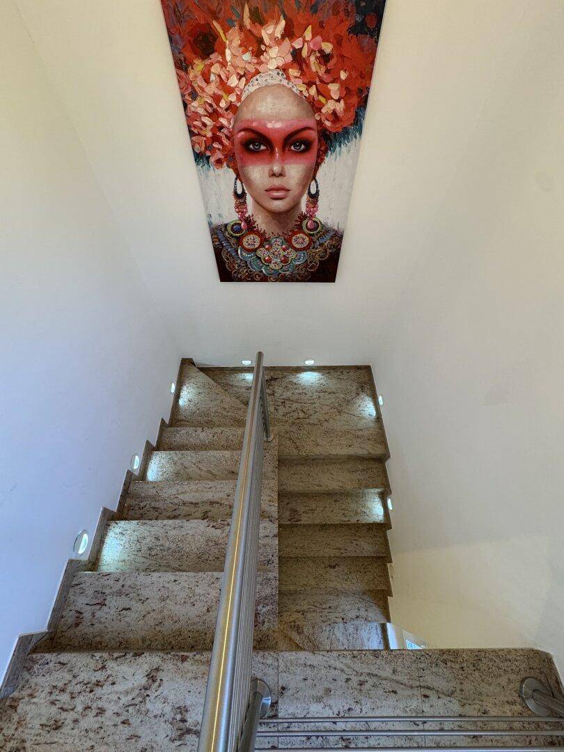 Elegante Treppe mit Steinbelag und integrierter Beleuchtung, geschmückt mit einem Kunstwerk.