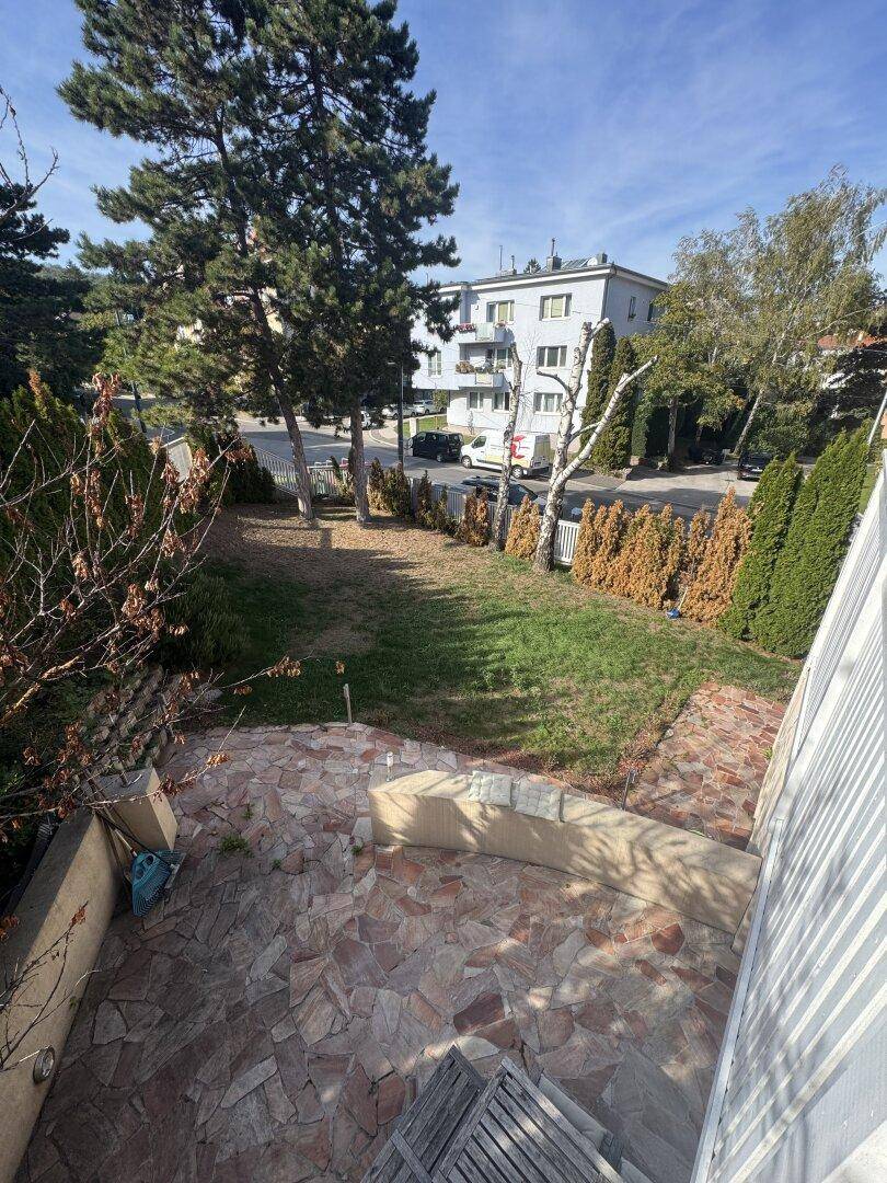Gartenbereich mit Steinplattenweg, Rasenfläche und Blick auf die umliegenden Gebäude.