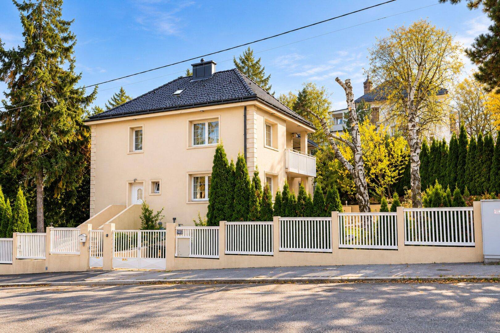 Attraktives Einfamilienhaus mit heller Fassade, gepflegtem Vorgarten und moderner Umzäunung.