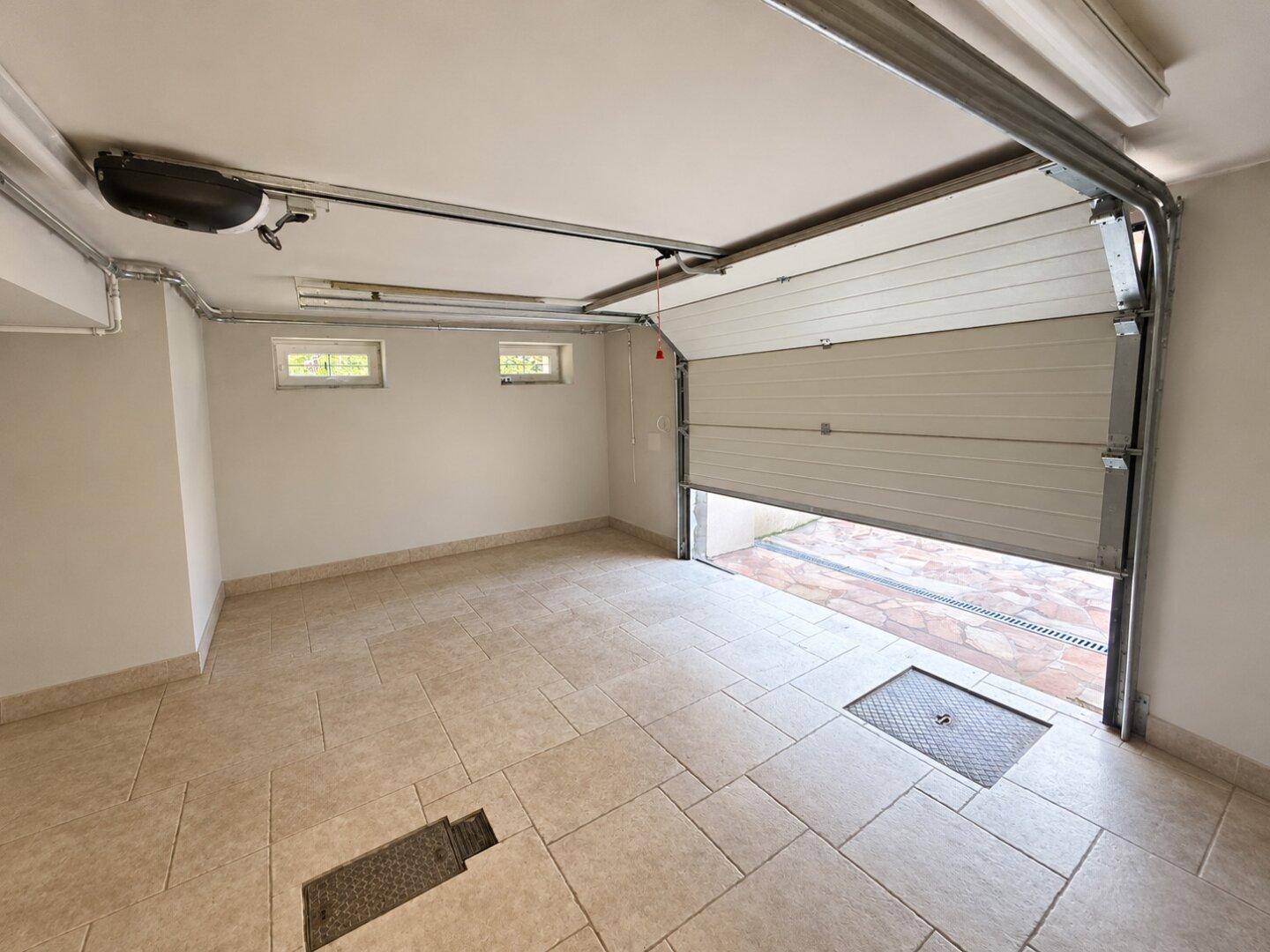 Geräumige Garage mit Fliesenboden und automatischem Garagentor, bereit zur Nutzung.