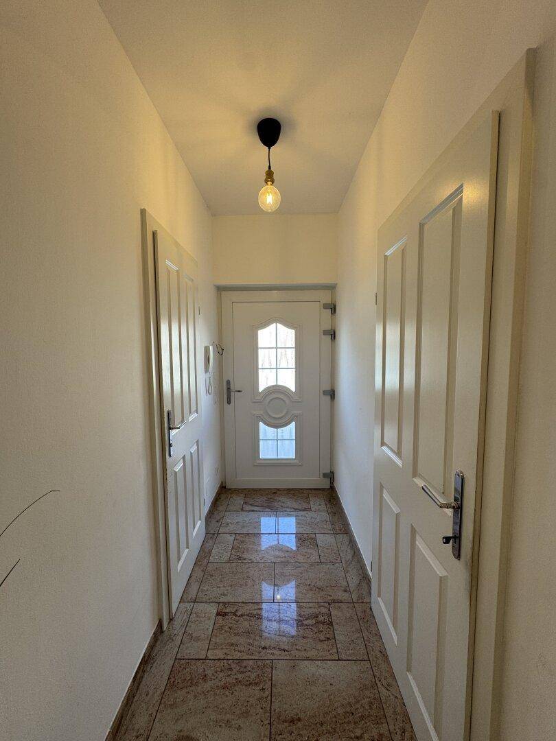 Heller Eingangsbereich mit Fliesenboden und Zugang zur Haustür.