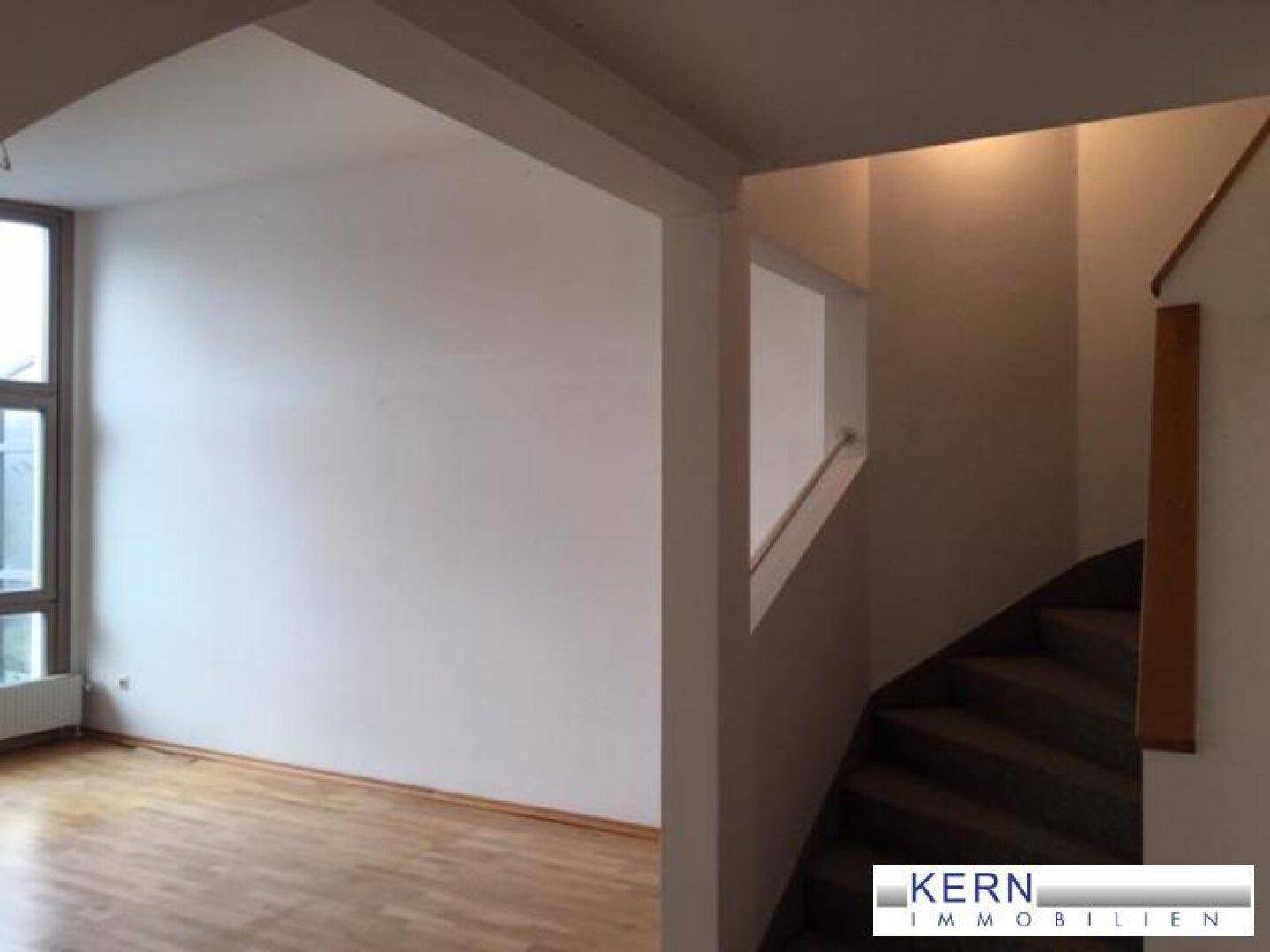 Treppenaufgang mit Holzstufen und weiß gestrichenen Wänden, verbindet die verschiedenen Ebenen.