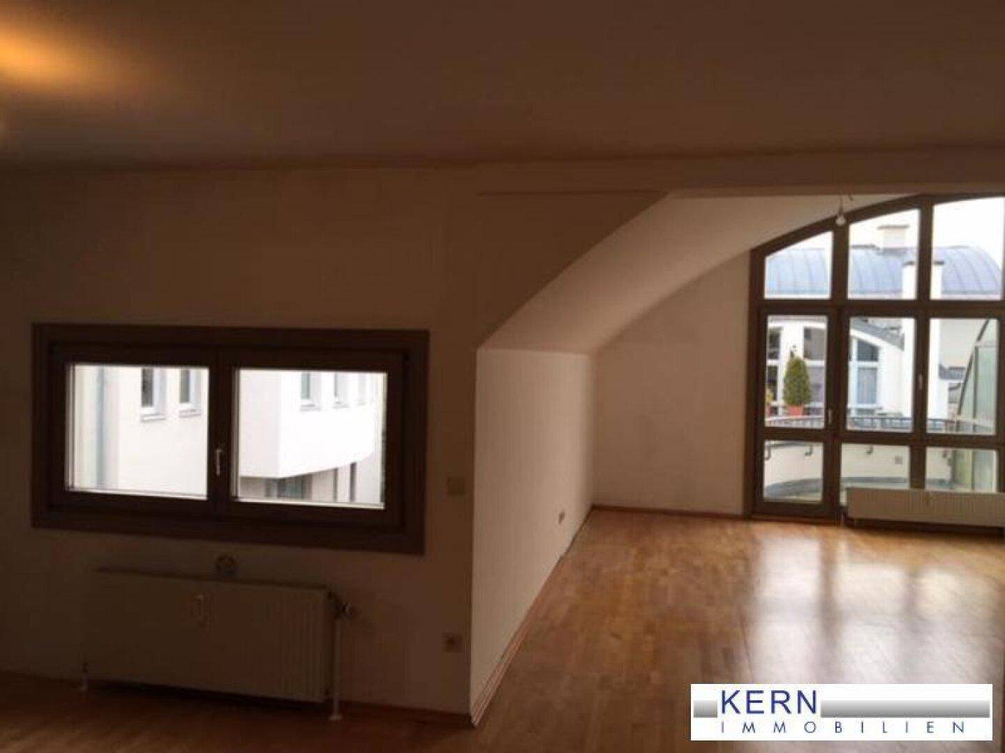 Geräumiges Wohnzimmer mit Holzboden, großen Fenstern und Dachschräge, ideal für individuelle Gestaltung.