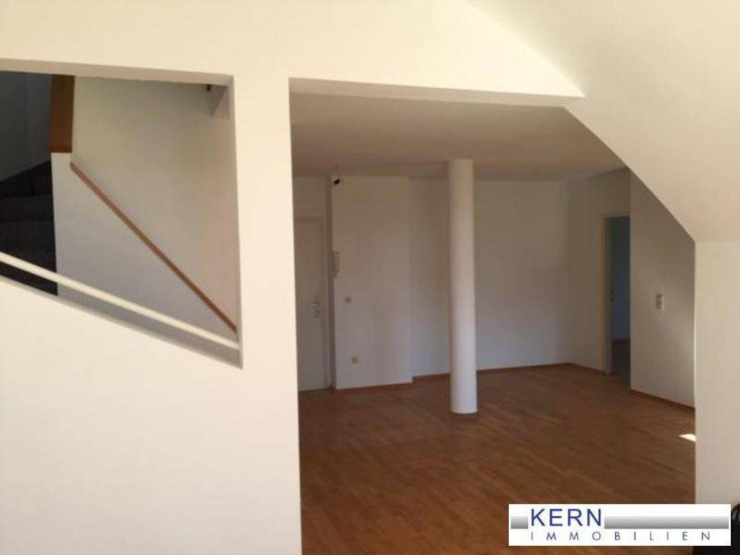 Offener Wohnbereich mit Holzboden und Treppenzugang, bietet flexible Gestaltungsmöglichkeiten.