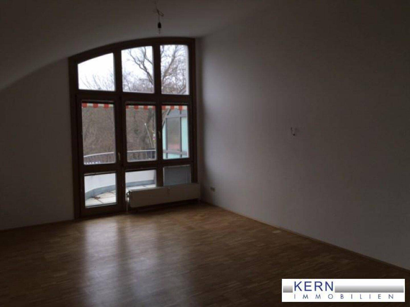 Leeres Zimmer mit großen Fenstern und Holzfußboden, bereit zur individuellen Gestaltung.