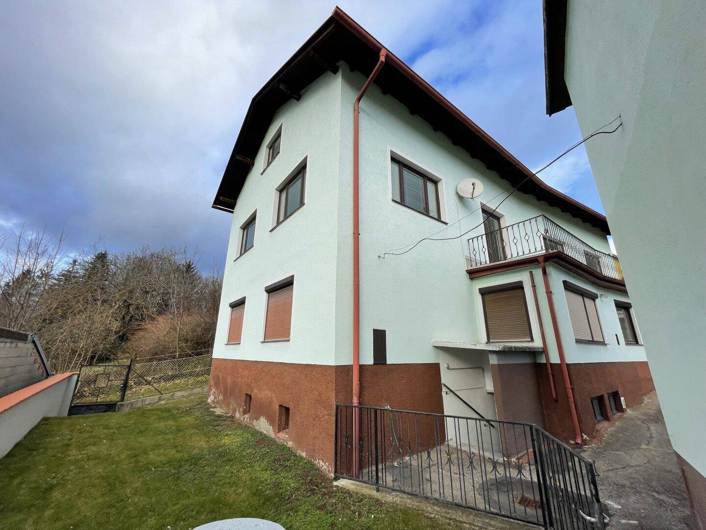 Seitenansicht des Hauses mit Gartenbereich, Balkon und Blick ins Grüne.