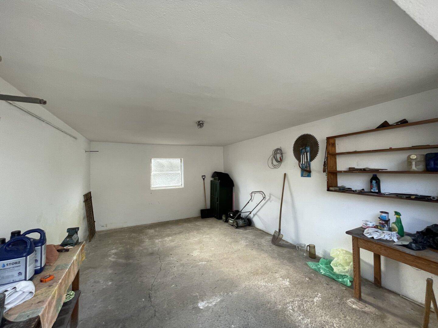 Geräumige Garage oder Werkstatt mit Betonboden und Werkzeugen.