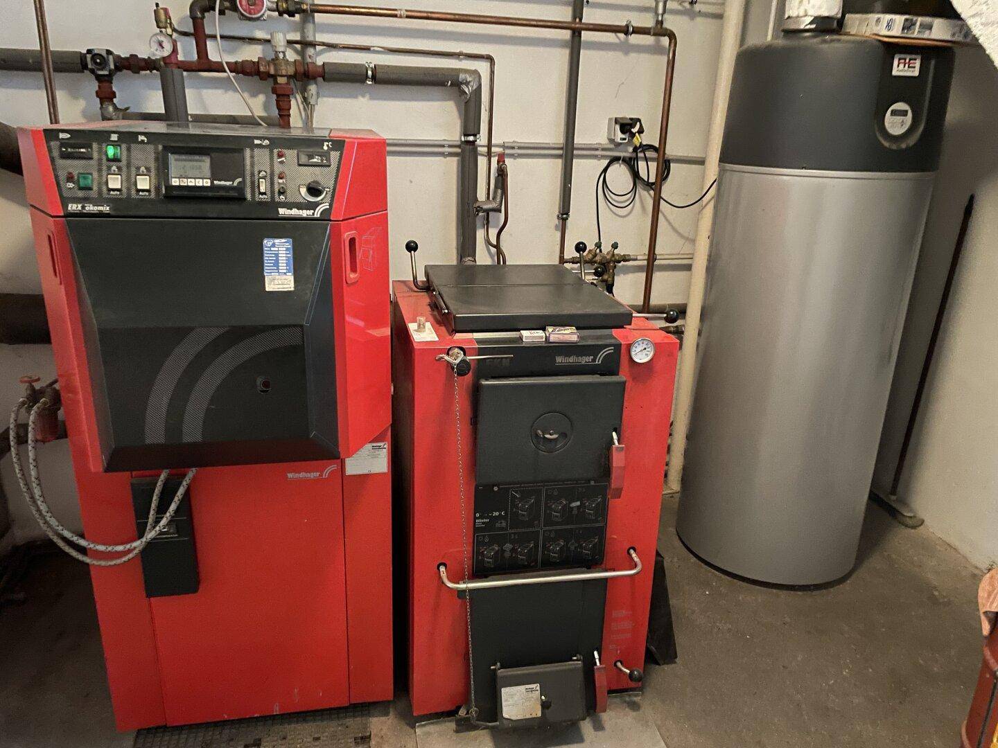 Heizungsraum mit zwei Heizkesseln und einem Warmwasserspeicher.