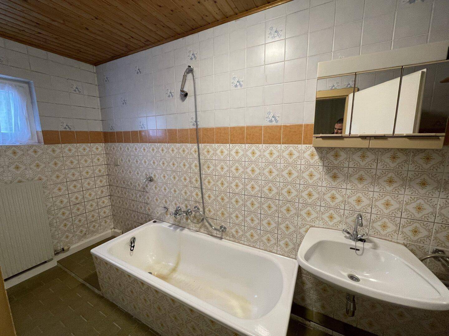 Badezimmer mit Badewanne, Waschbecken, Fliesen und Holzdecke.