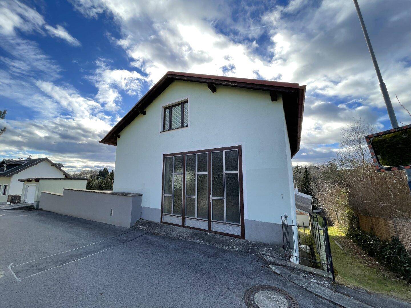 Seitenansicht eines Nebengebäudes mit großem Tor und Satteldach.