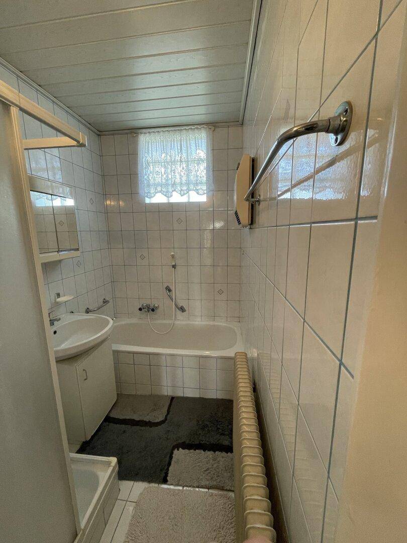Gefliestes Badezimmer mit Badewanne, Waschbecken und Fenster.