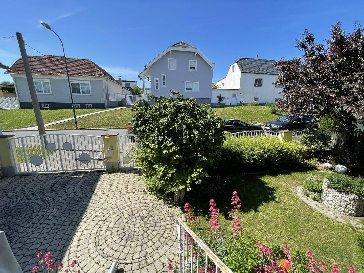 Vorgarten mit gepflastertem Eingangsbereich und Blick auf die Nachbarschaft.