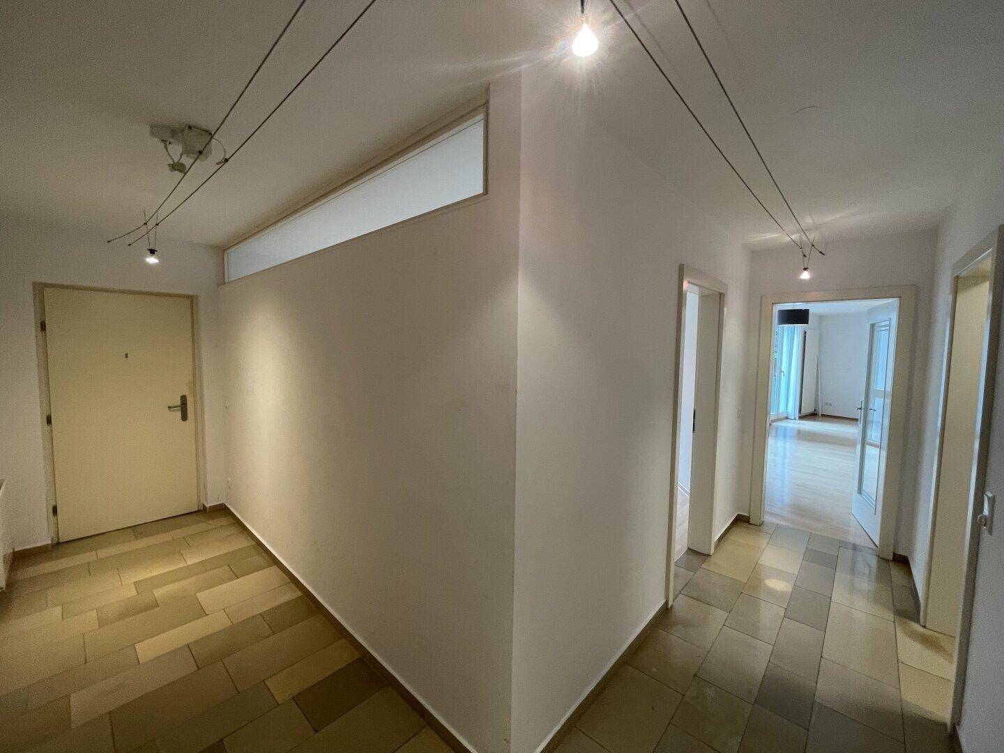 Heller Flur mit Fliesenboden und Zugang zu verschiedenen Räumen der Wohnung.