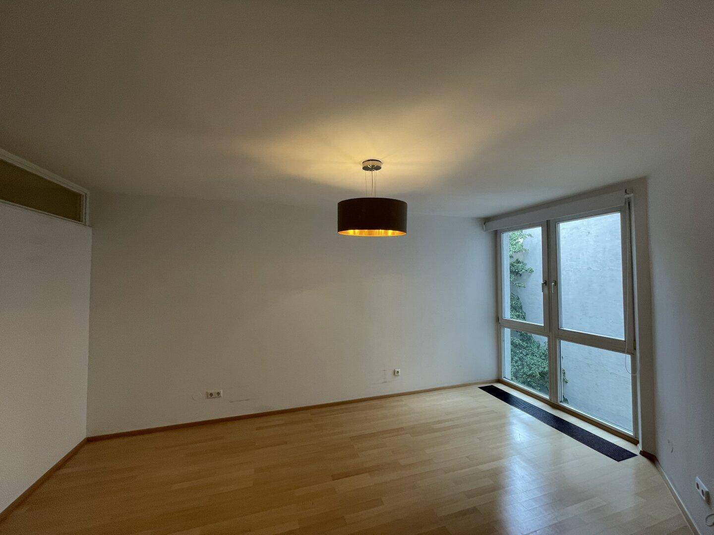 Ruhiges Zimmer mit Parkettboden und Fenster mit Blick ins Grüne, ideal als Schlafzimmer.