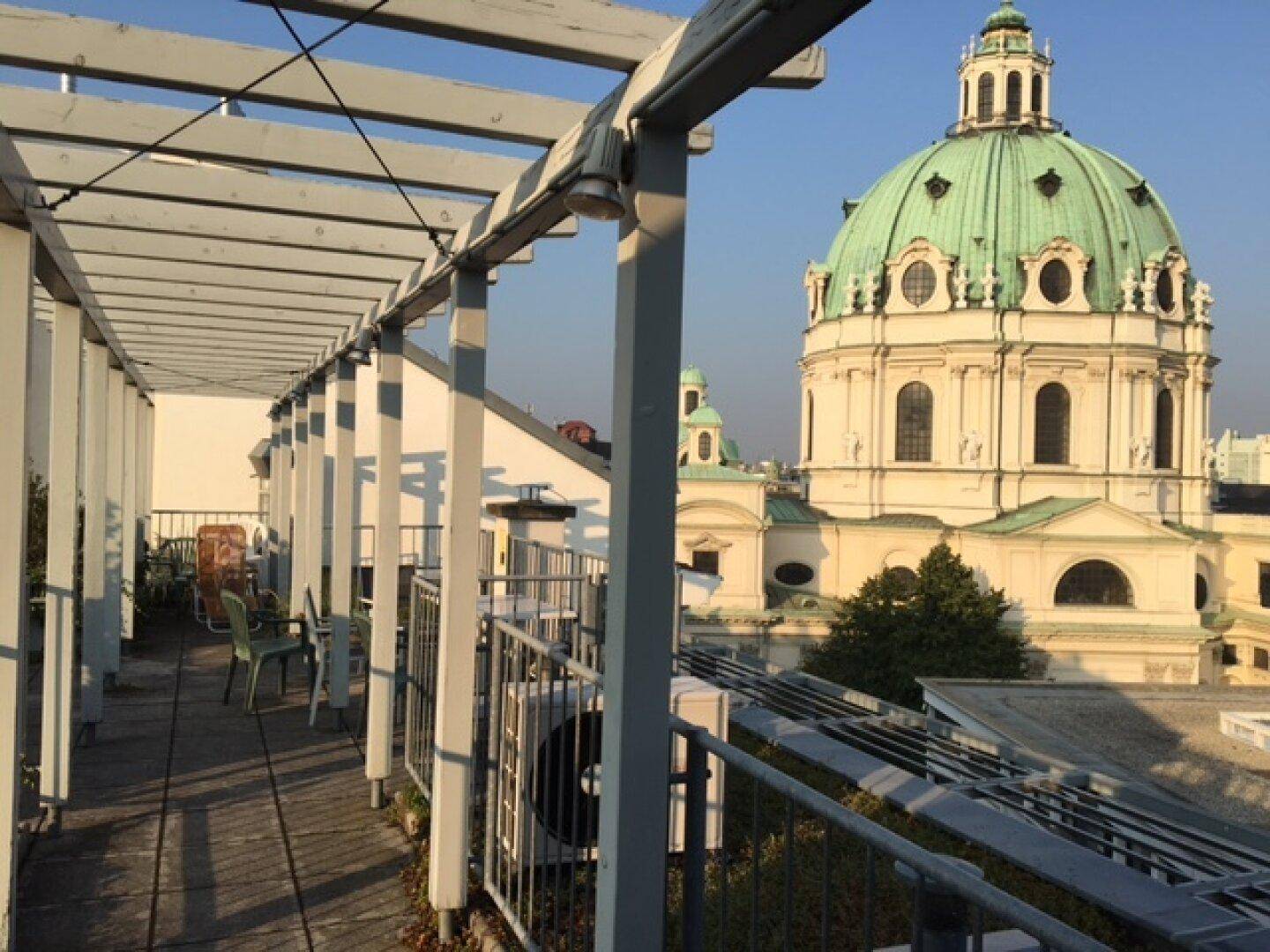Dachterrasse mit Pergola und beeindruckendem Blick auf eine historische Kirche.