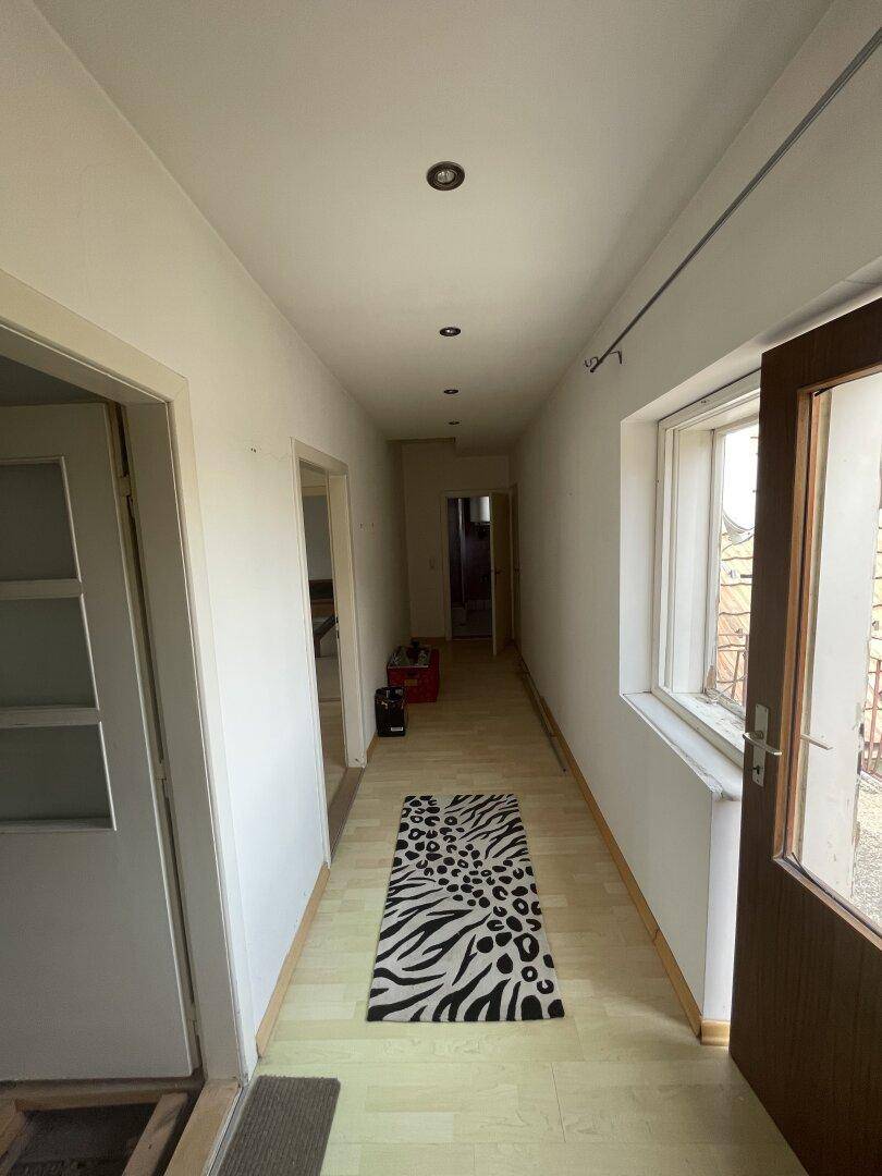 Langer Flur mit Laminatboden, weißen Wänden und einer modernen Deckenbeleuchtung.