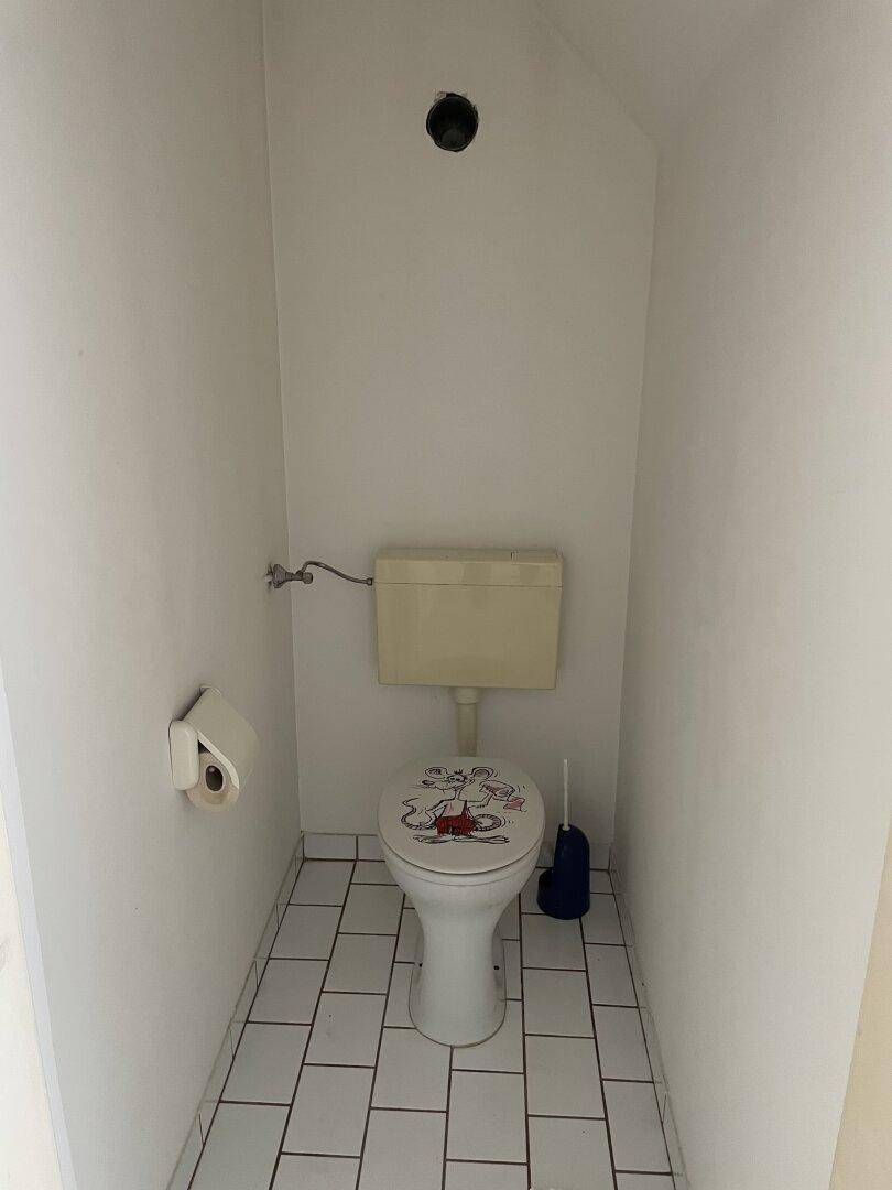 Kleines WC mit weißen Fliesen, einer Toilette und einem einfachen Design.