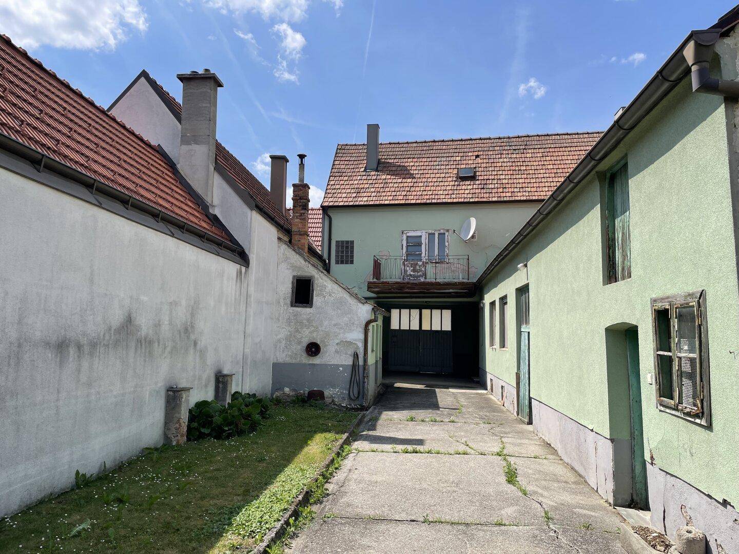 Blick auf den Innenhof oder Durchgang zwischen den Gebäuden mit einem Balkon im Hintergrund.