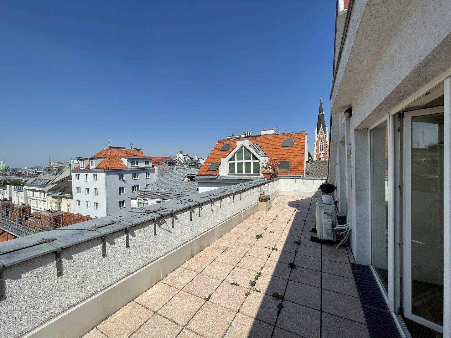 Große Dachterrasse mit Fliesenboden und weitem Blick über die städtischen Dächer.